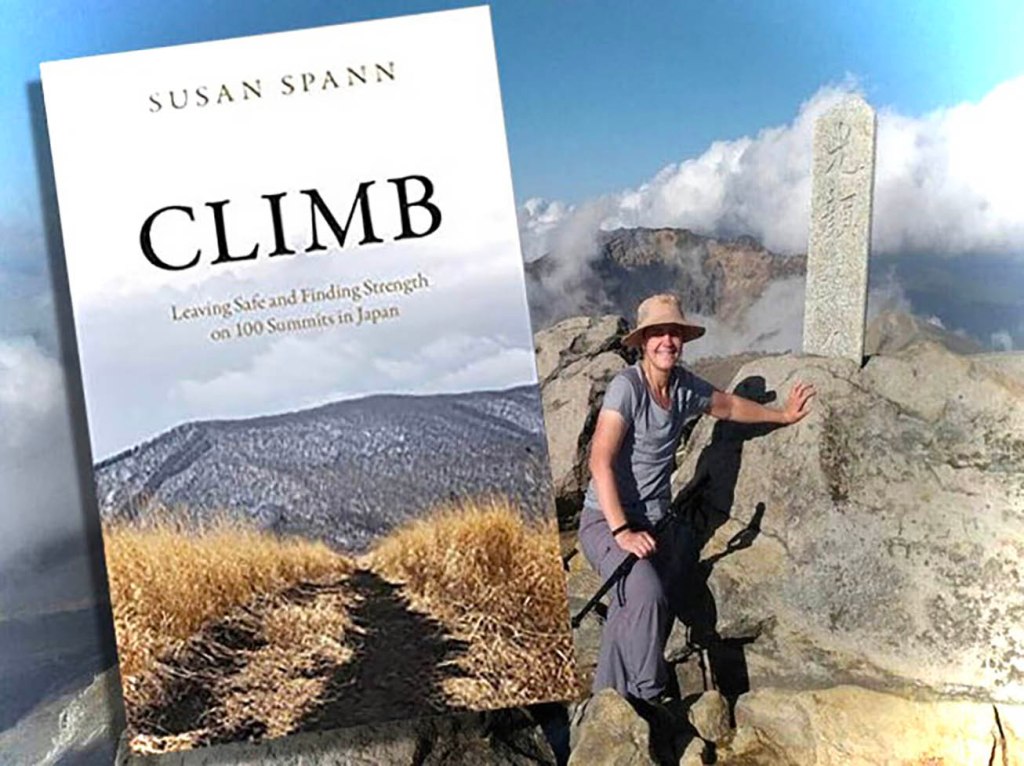 Author Susan Spann on a mountaintop with the covr of her memoir CLIMB