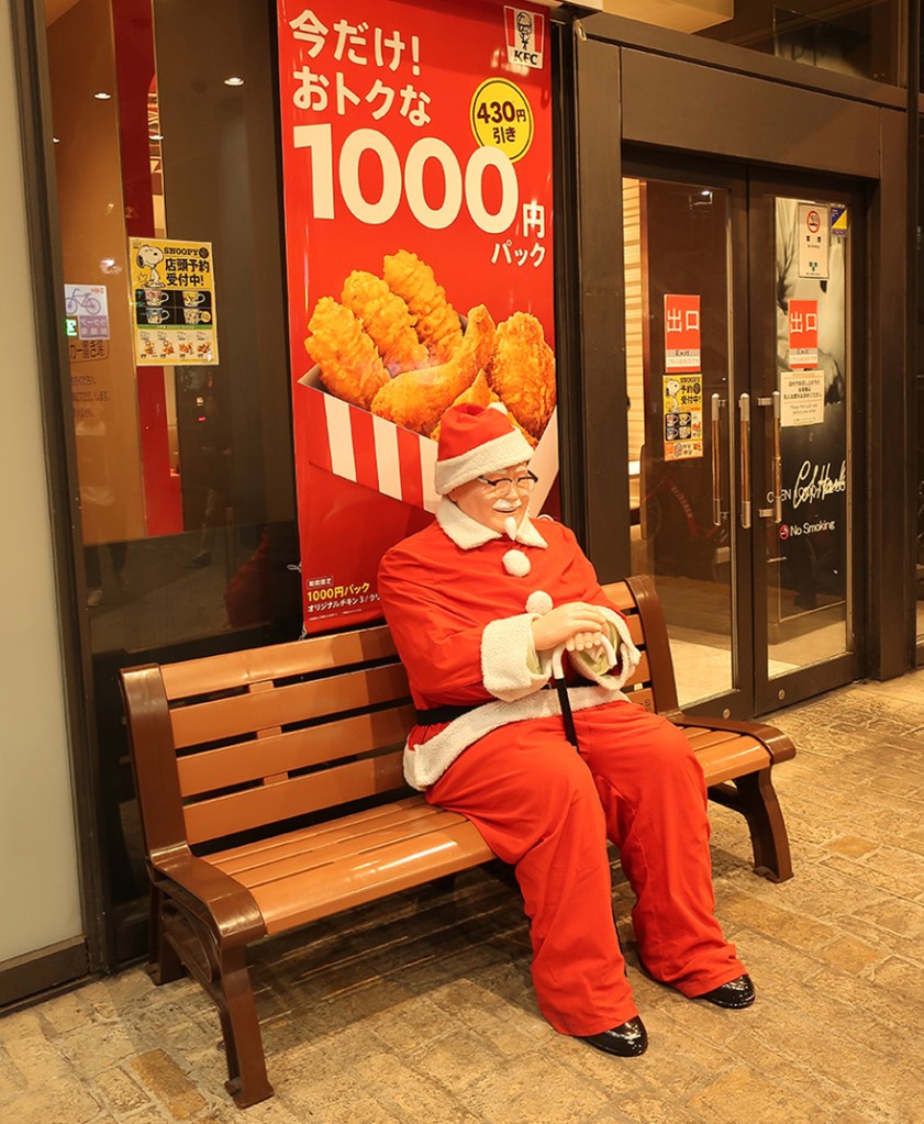 Colonel Sanders dressed as Santa outside KFC