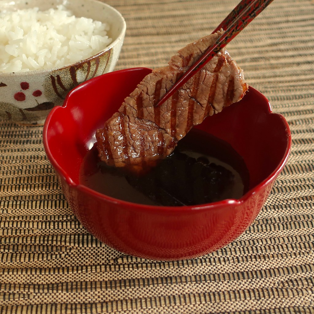 Dipping slice of steak in Japanese ginger-soy steak dipping sauce