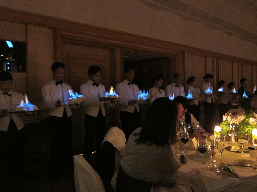 Waiters serving flaming Baked Alaska at a Japanese wedding