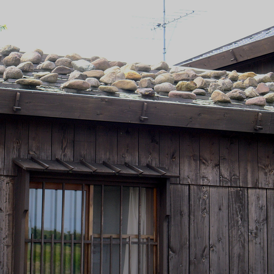 Rock weighing down a roof on Sado Island
