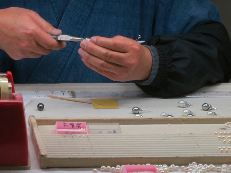 Worker stringing pearls