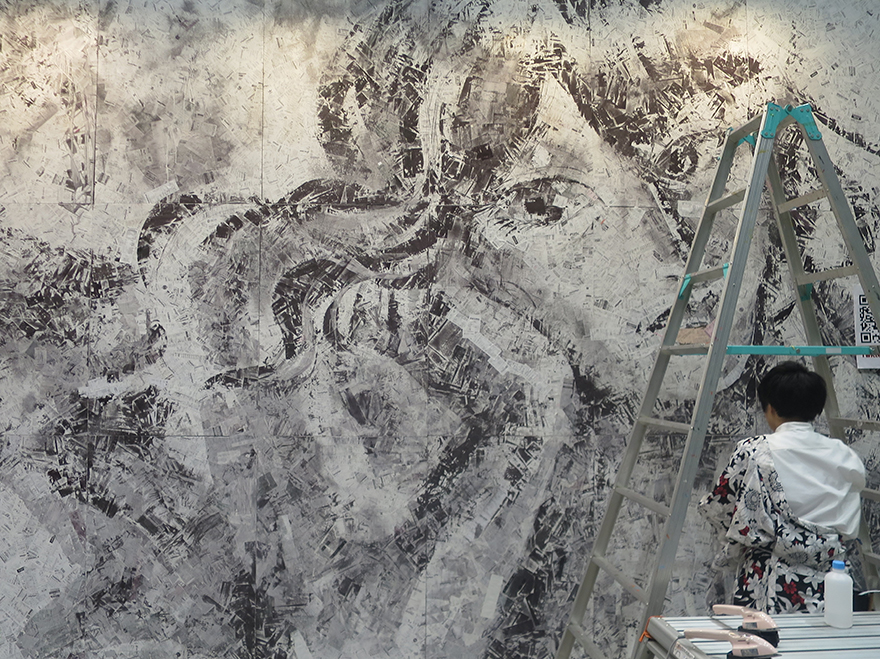 Mural of a woman's face made of trash & receipts at Design Festa