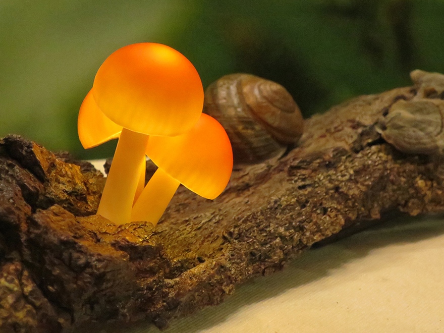 Glowing glass mushrooms on log at Design Festa