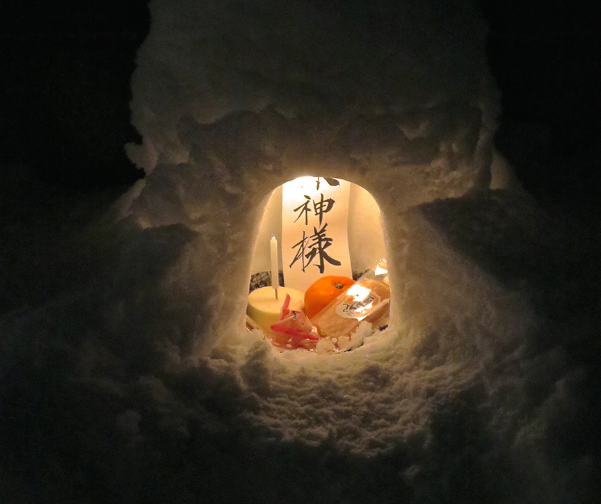 Adult offering inside lighted igloo at the Kamakura Matsuri